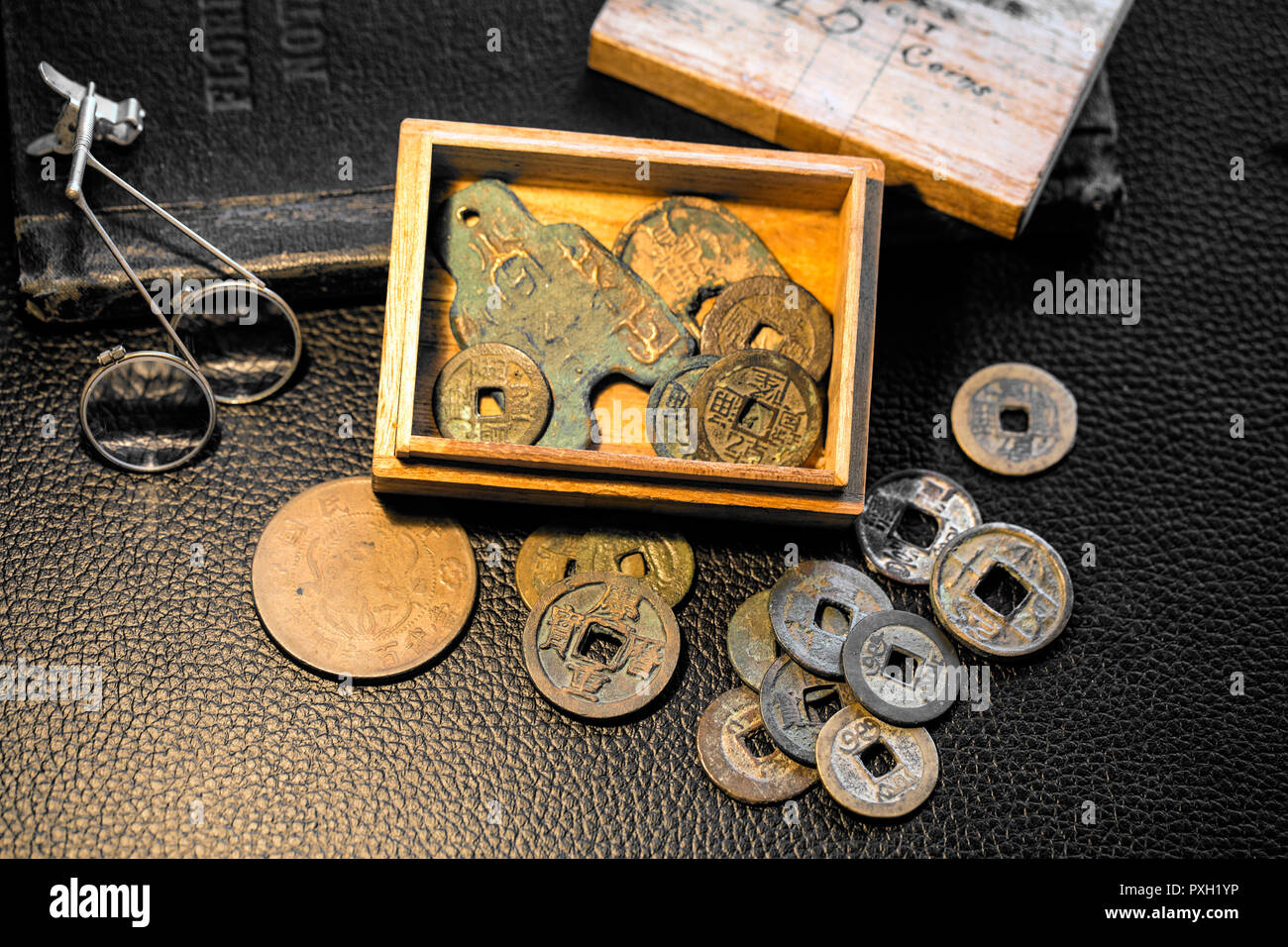 Young boy's balsa wood box 'Keep out' 'Old Coins' full of ancient China and Japan bronze, metal cash coinage-with patina of age. Stock Photo