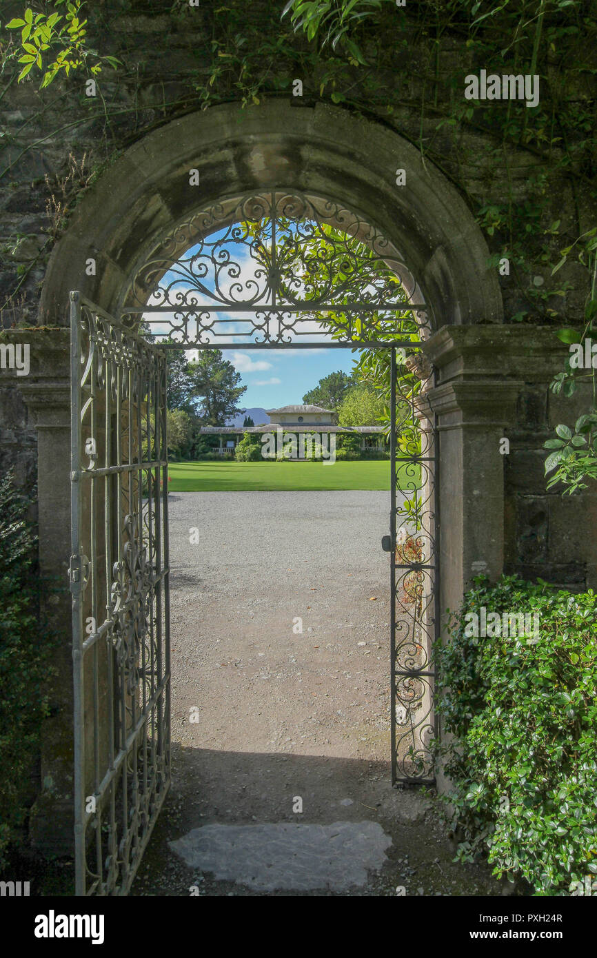 Arch and metal gate out of the walled garden on Garnish Island, County Cork, Ireland heading towards the Italian Tearoom and garden. Stock Photo
