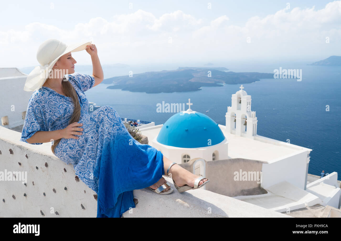young woman in a white and blue dress enjoys a walk around Santorini Stock Photo