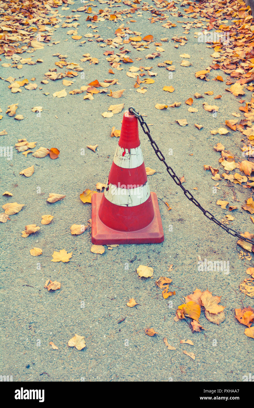 Traffic cone with rust chain and dry fallen autumn leaves on the ...