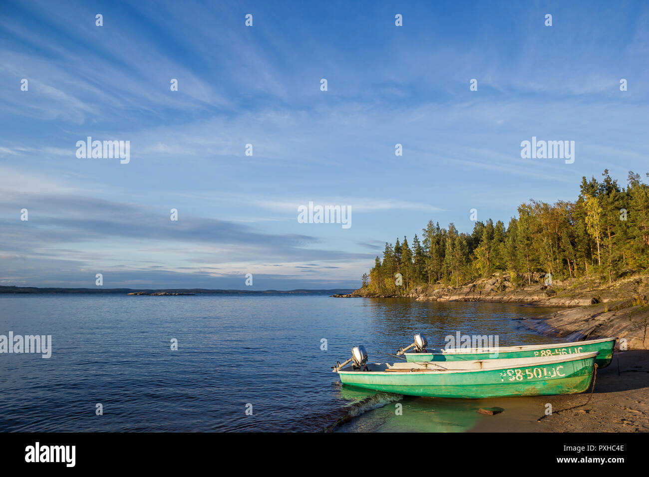 Blue Sky above Water and Beach at  Lake with Two Green Pella Boats Stock Photo