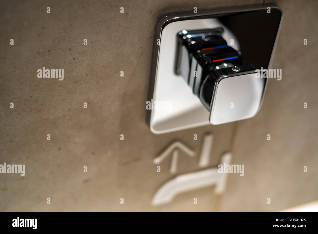 Chrome button to start tap water in public toilet Stock Photo