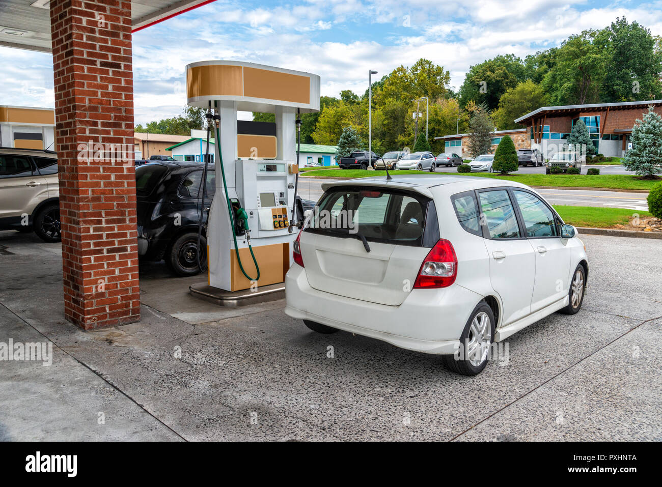Horizontal shot of a Generic Compact Car Buying Gasoline At a Generic Convenience Store.  All visible markings and signs have been removed. Stock Photo
