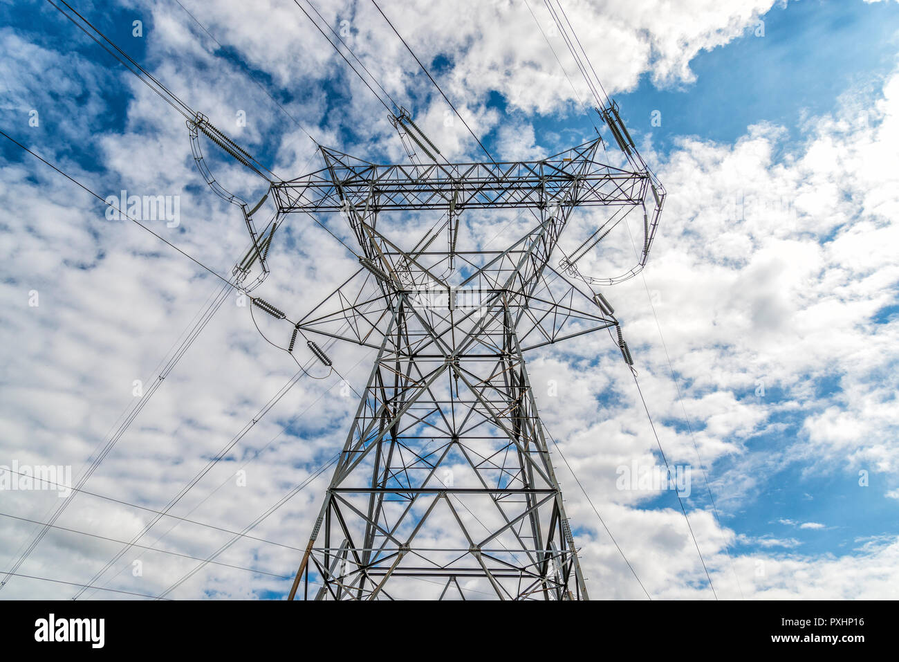 Horizontal shot of a High Voltage Tower and Power Lines under cloudy skies. Stock Photo