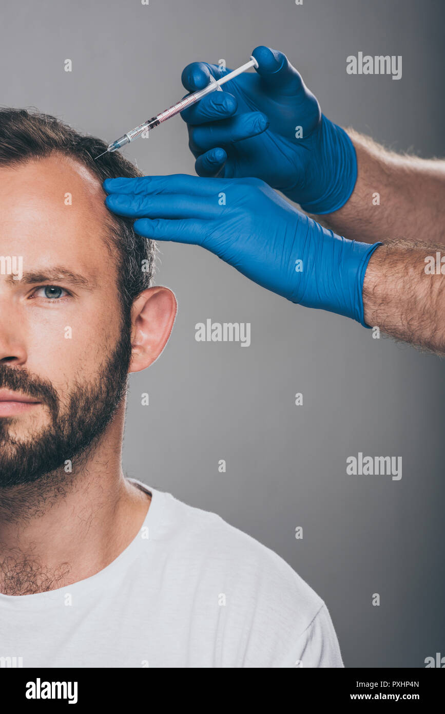 cropped shot of doctor with syringe giving injection to man with ...