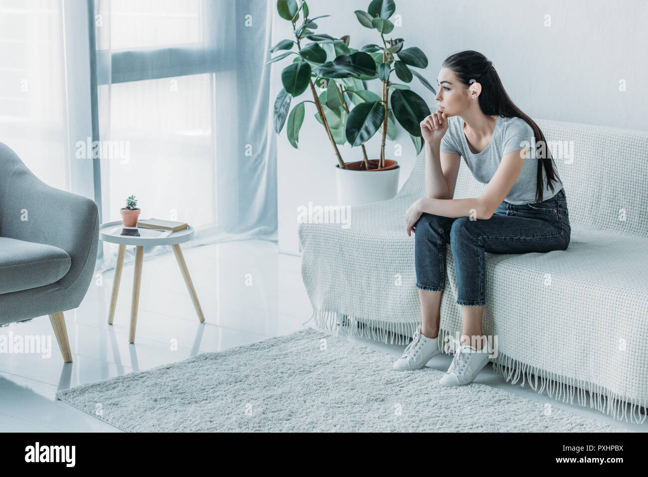 high angle view of sad young woman in depression sitting on couch and ...