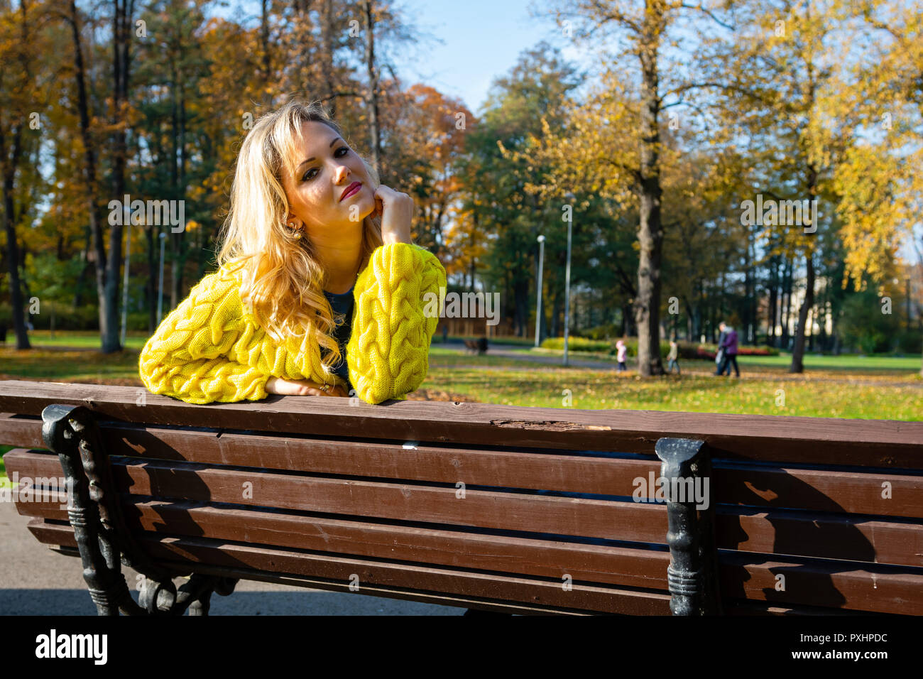 A young, beautiful, blonde woman sitting in a park on a bench Stock ...