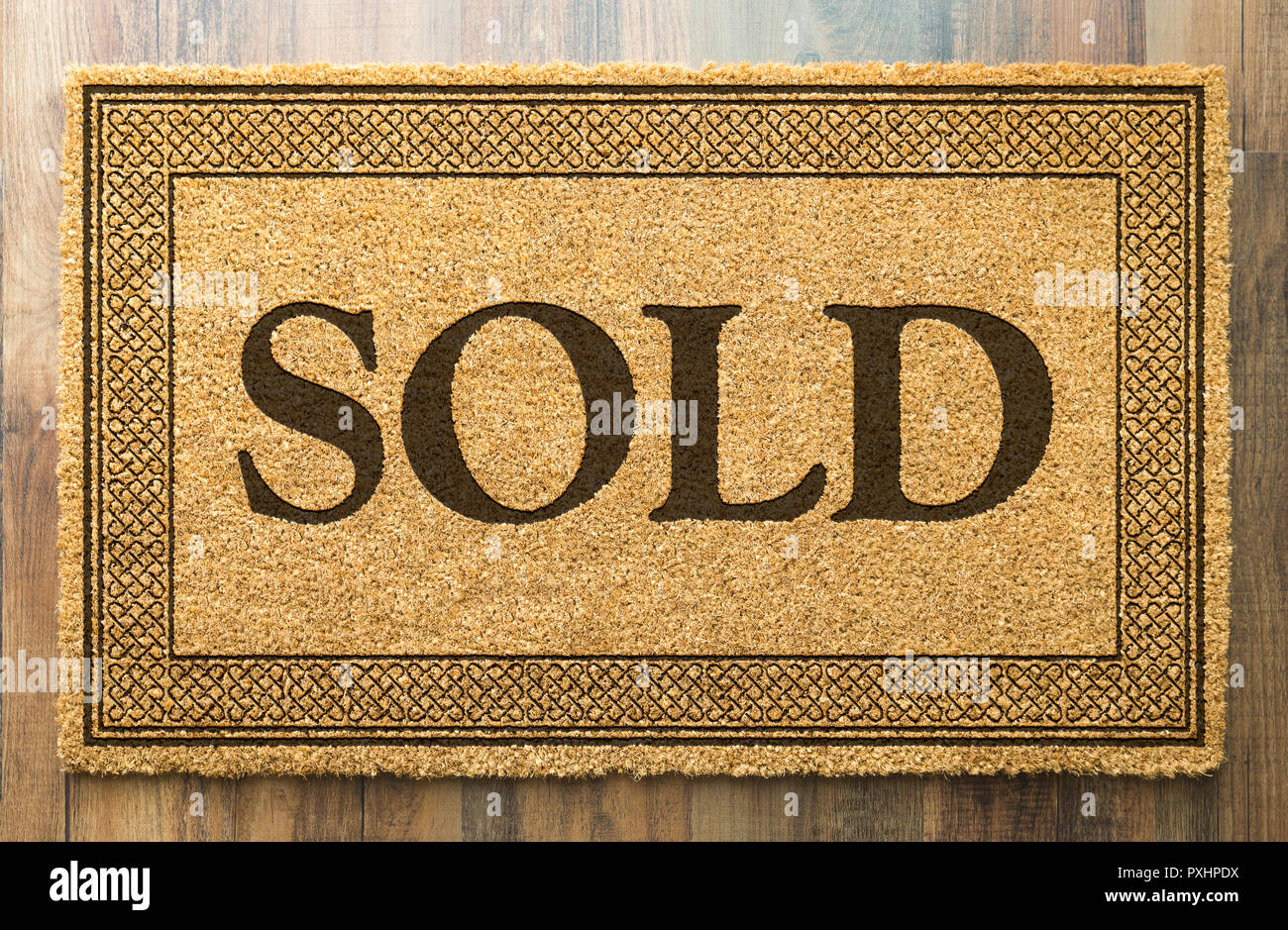 Sold Welcome Mat On A Wood Floor Background. Stock Photo
