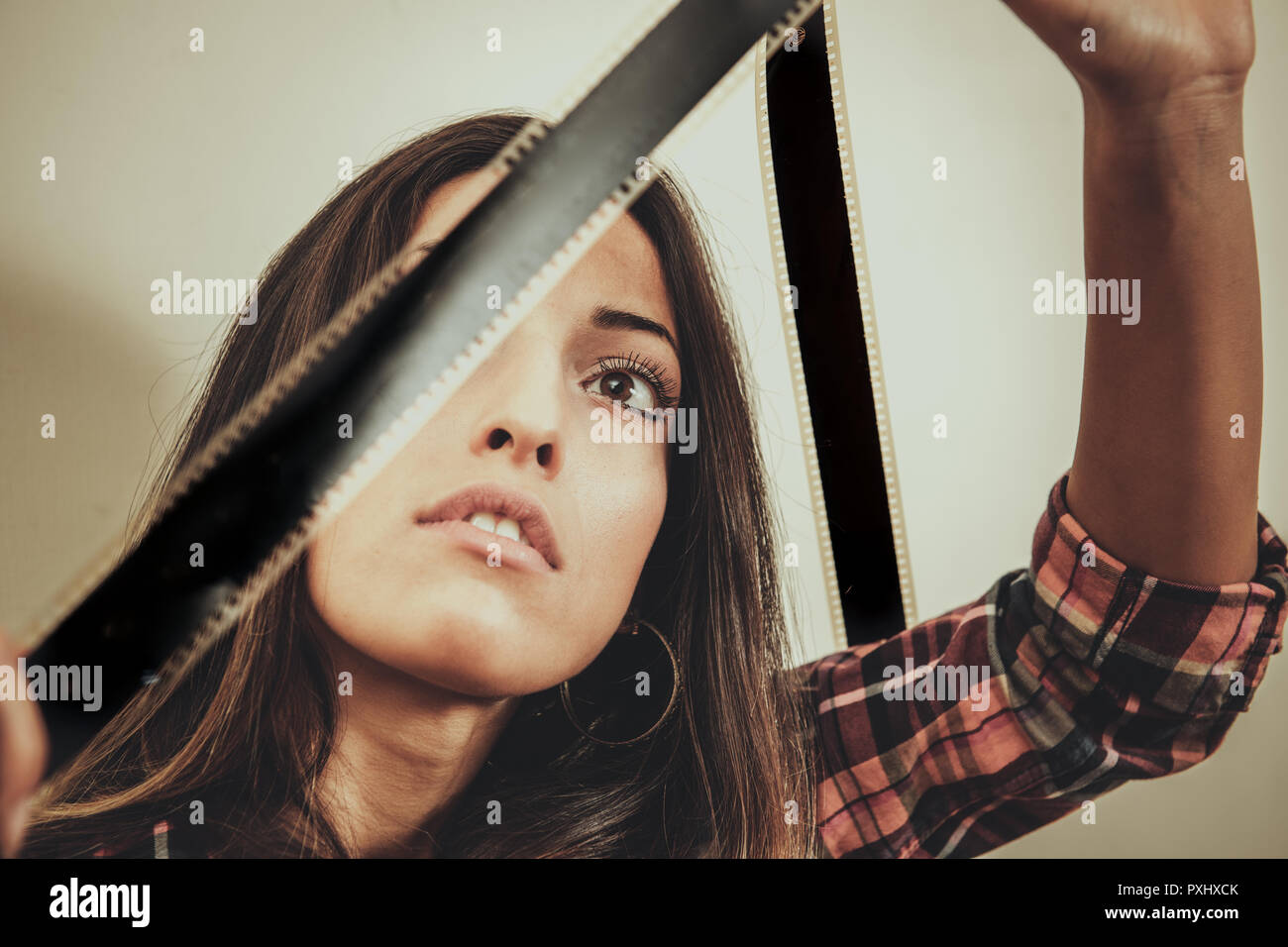 Portrait of young beautiful woman looking at movie filmstrip against the light vintage style Stock Photo