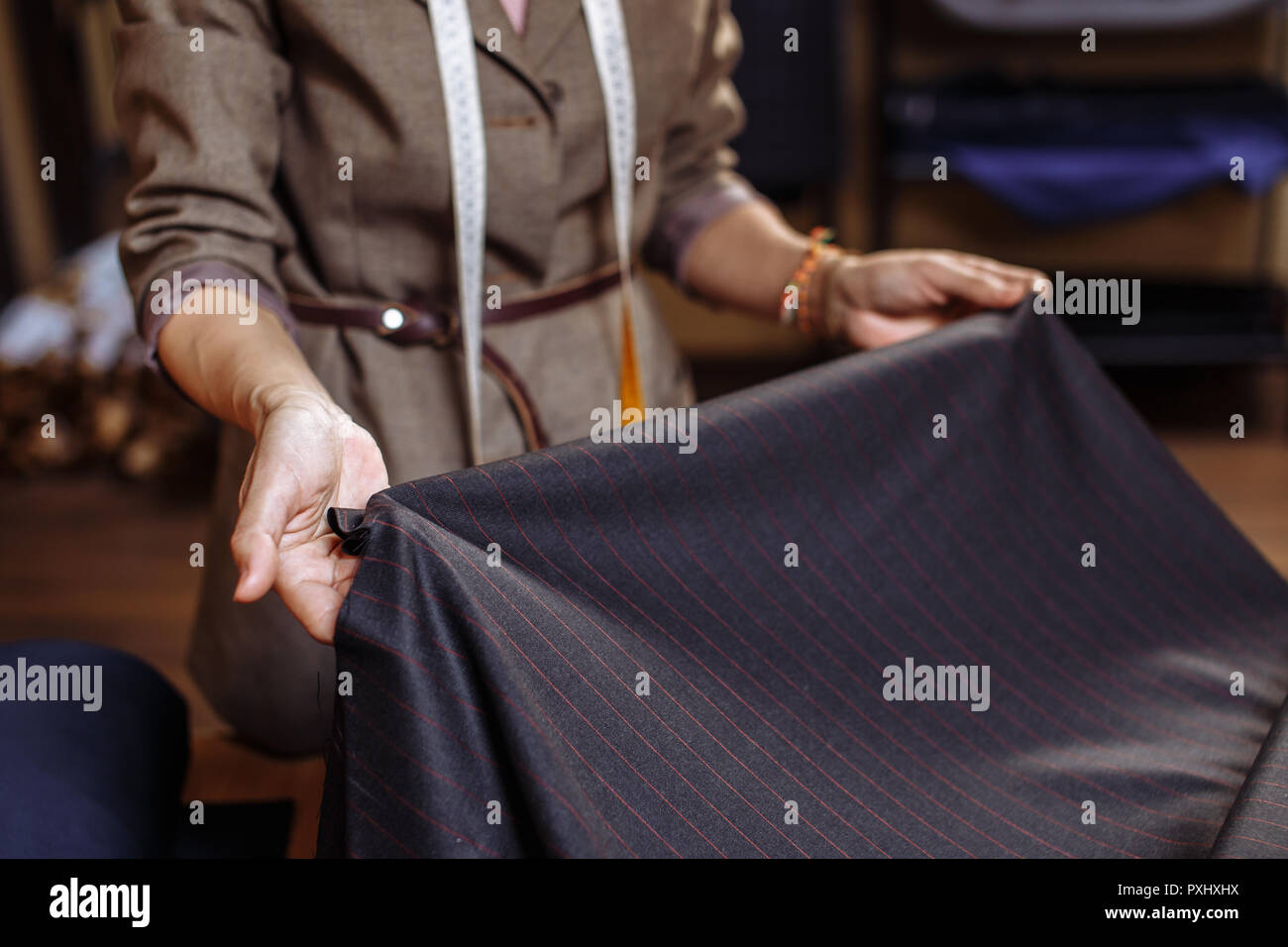 Female tailor choosing fabric for pattern cutting. Men's Wear industry ...