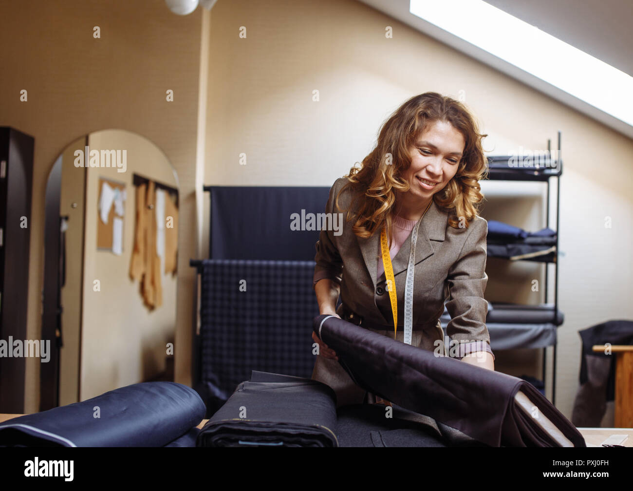 Female tailor choosing fabric for pattern cutting. Men's Wear industry ...