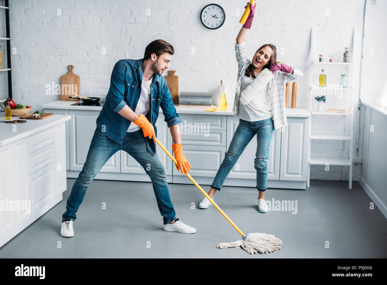 couple in rubber gloves having fun with mop during cleaning kitchen Stock  Photo - Alamy