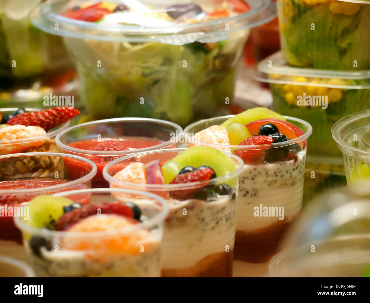 Healthy food on display, ripe fruit and yoghurt, small portions on sale, closeup Stock Photo