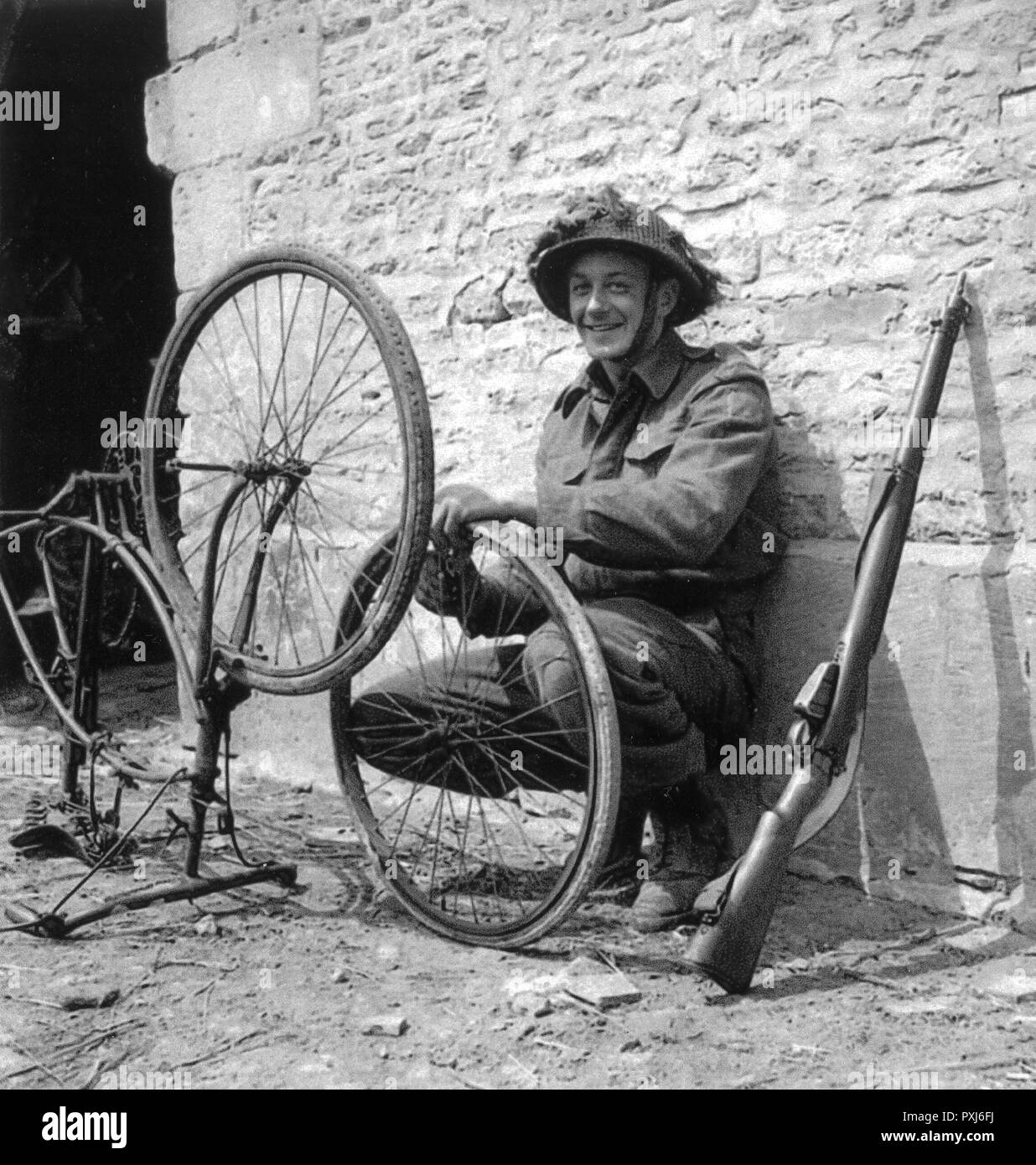 WW2 - Canadian Trooper repairing his bicycle in Normandy Stock Photo