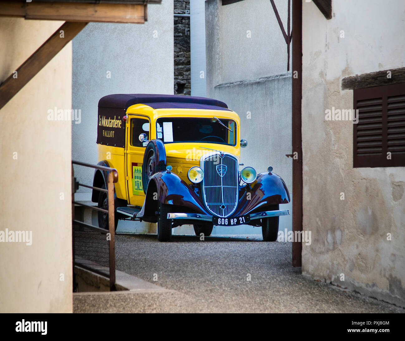 Vintage car in narrow alley of mustard factory Edmont Fallot  in Beaune, France. A delivery vehicle from a bygone era stands in the courtyard of Moutarderie Edmond Fallot Stock Photo