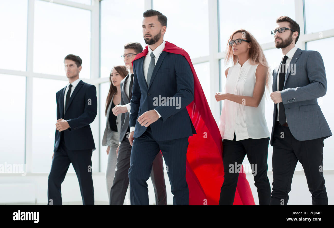businessman in Superman cloak and business team standing in offi Stock Photo