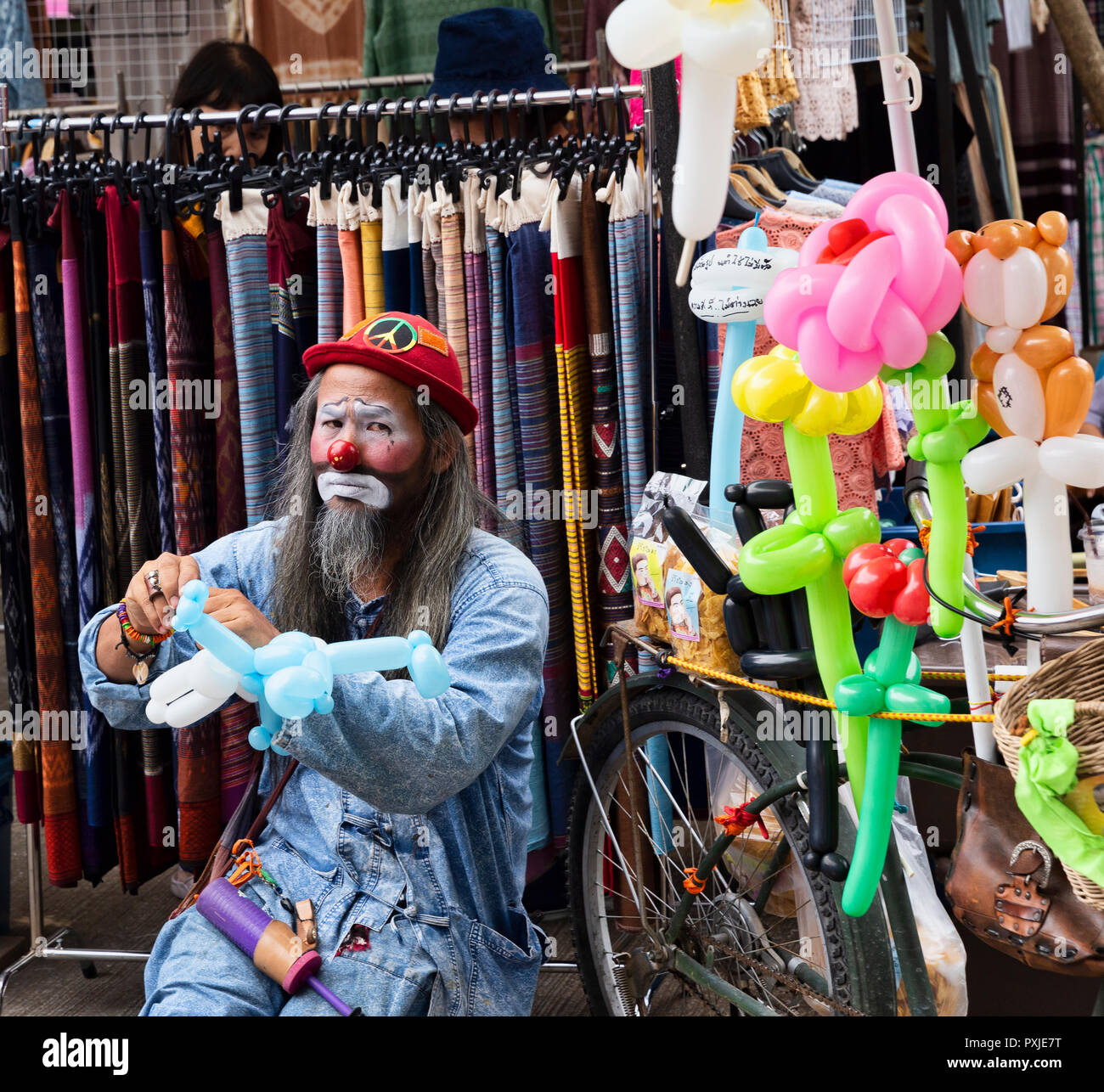 Clown with sad face making balloon animals, JingJai Farmer's Market, Chiang Mai, Thailand Stock Photo