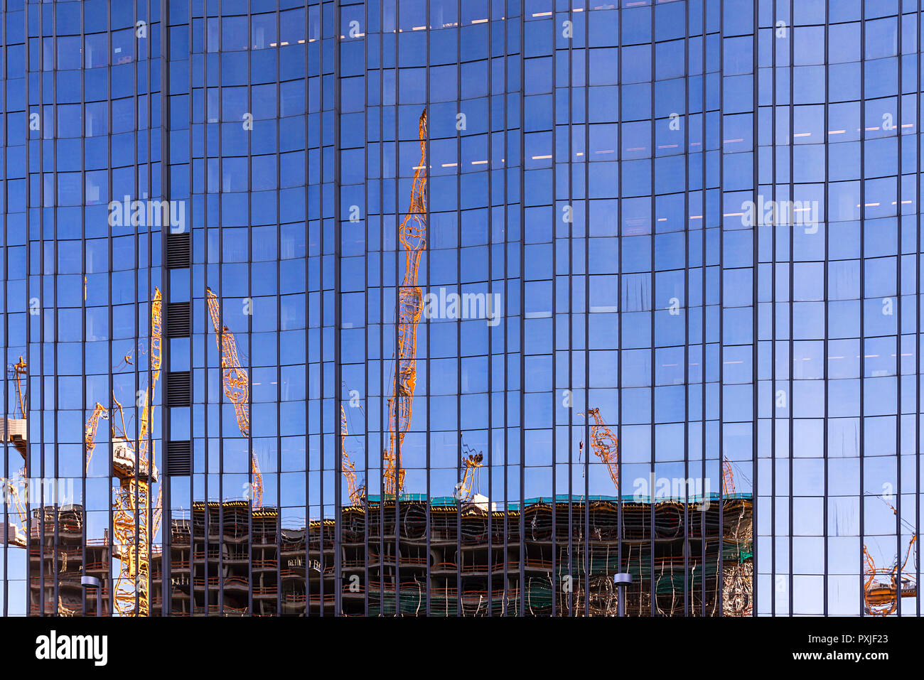 Building cranes and building site of the New Palace reflected in a glass facade of a high-rise building, Berlin, Germany Stock Photo
