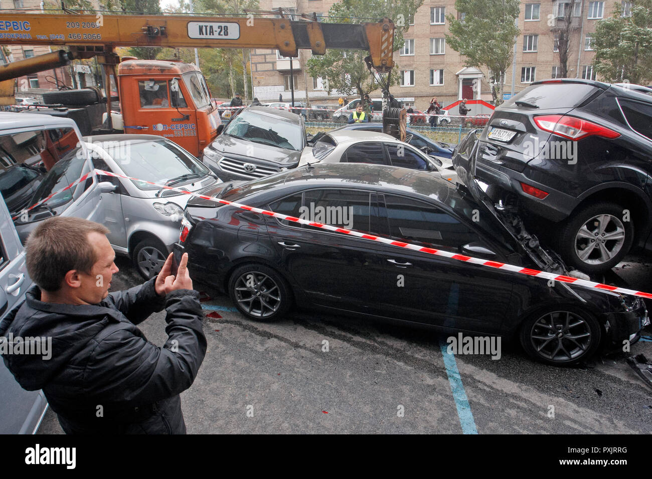 Kiev, Ukraine. 23rd October, 2018. A man seen taking a picture of damaged cars during a large-scale road traffic accident in center of Kiev. As local media reported, about 17 cars was rammed and damaged after a mobile truck crane with non-working brakes crashed into passenger cars, according to preliminary data. Credit: SOPA Images Limited/Alamy Live News Stock Photo