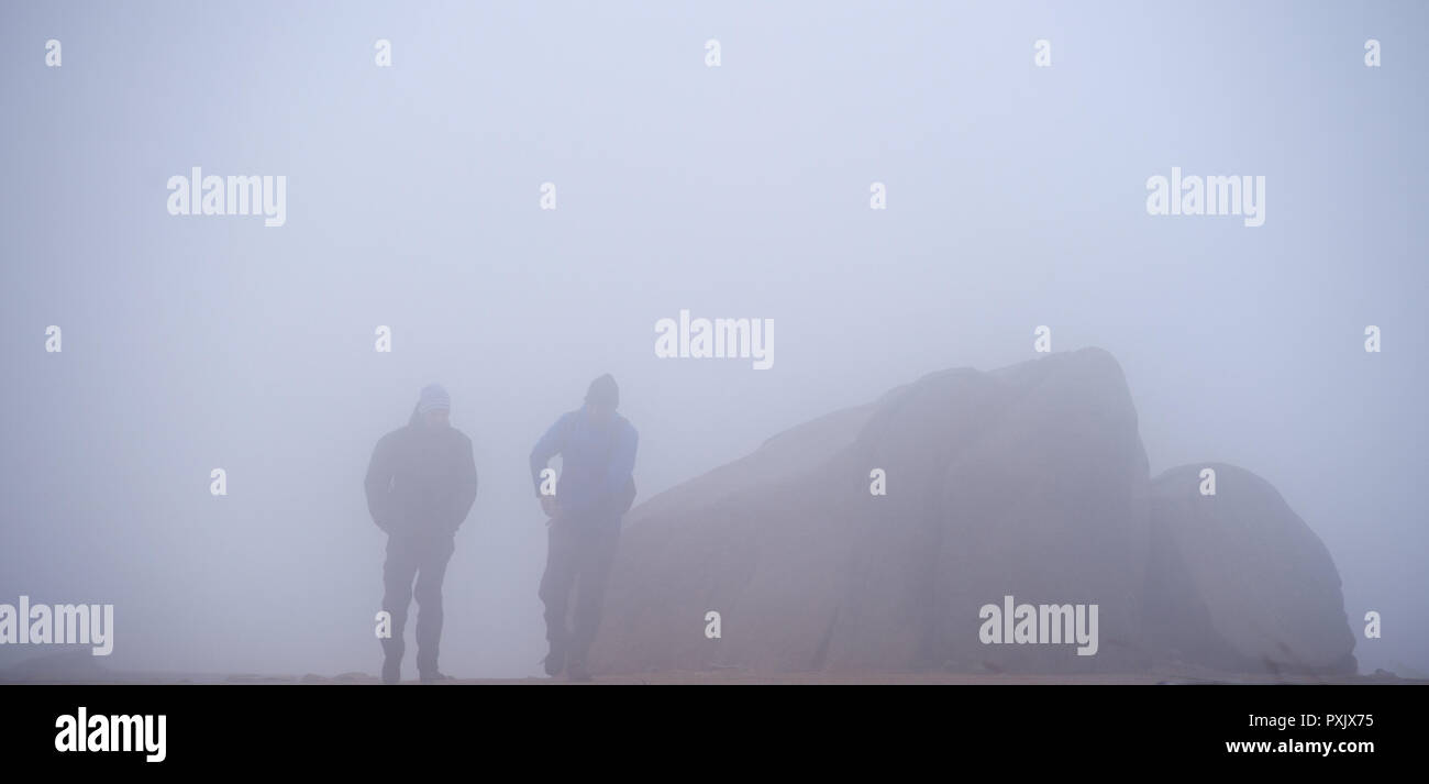 23 October 2018, Saxony-Anhalt, Brockengipfel: Hikers walk over the Brocken plateau in rain, fog and storm. The German Weather Service (DWD) has issued a thunderstorm warning for the Harz Mountains. The Harzer Schmalspurbahnen (HSB) have stopped the train service to the summit of the Brocken and are now only running to Drei Annen Hohne station. Photo: Klaus-Dietmar Gabbert/dpa-Zentralbild/dpa Stock Photo