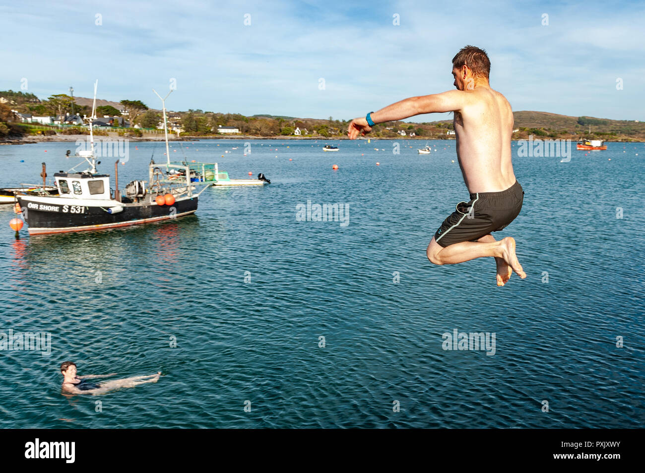 Schull, West Cork, Ireland. 23rd Oct, 2018.  Clinton Copithorne from Ballydehob makes the most of the unseasonably warm weather by jumping into the sea off Schull Pier. Sunshine has been the order of the day today with highs of 13-15° Celsius in West Cork. Credit: Andy Gibson/Alamy Live News. Stock Photo