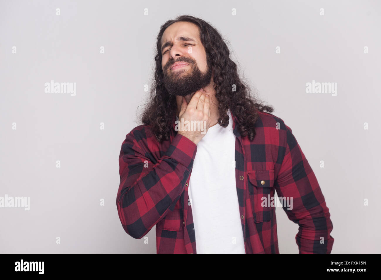 Portrait of sick handsome man with beard and black long curly hair in casual  style, checkered red shirt standing with pain on his neck and closed eyes  Stock Photo - Alamy