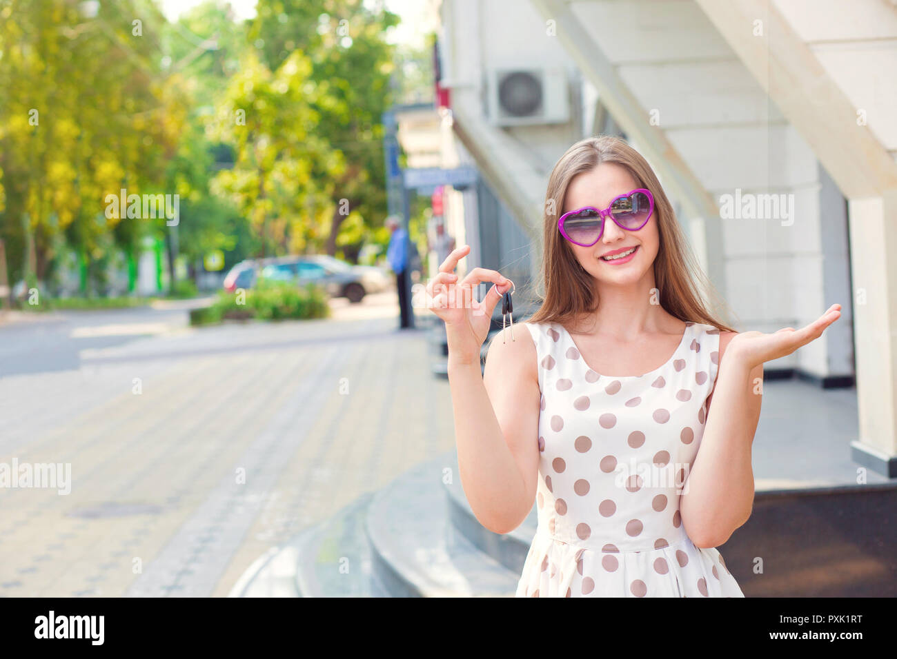 Smiling girl holding keys showing the building Stock Photo - Alamy