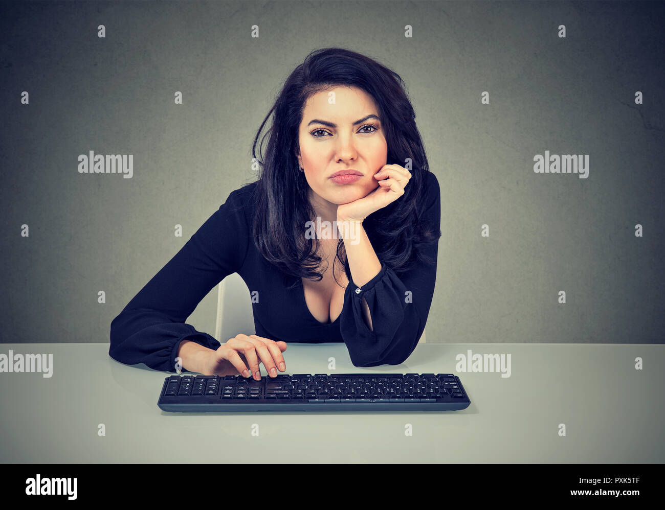 Young woman sitting at workplace and procrastinating being lazy and distracted feeling bored Stock Photo