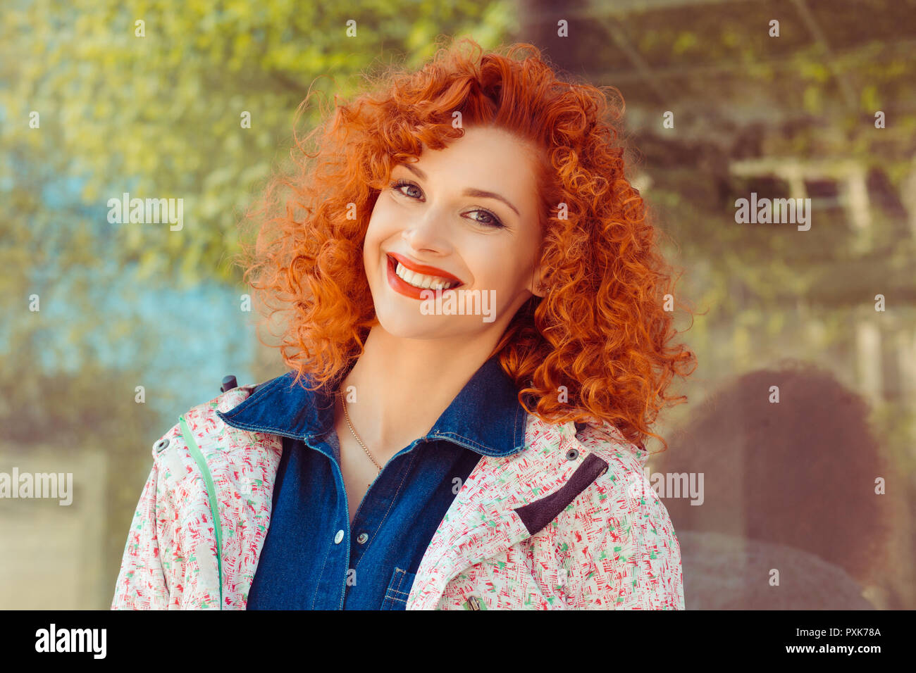 Happy cheerful young woman with curly redhead ginger hair rejoicing at positive news Stock Photo