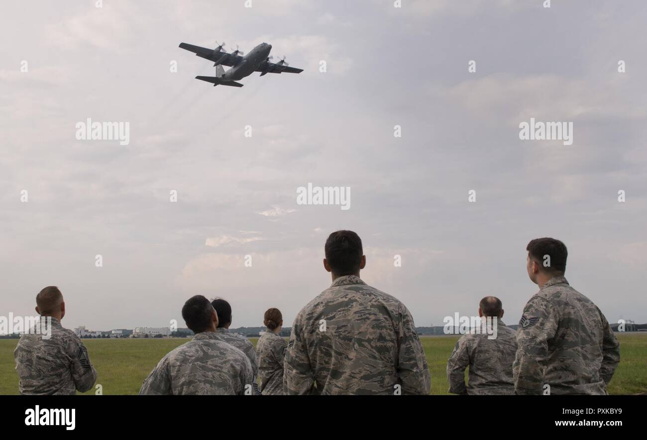 Members with the 374th Civil Engineer Squadron look up at a C-130 Hercules flying over the flightline during an annual certification test of the Aircraft Arresting System at Yokota Air Base, Japan, June 1, 2017. Airmen from the 374 CES and 374th Operations Support Squadron are responsible for setting up the system and logging any deficiencies during the test. Stock Photo