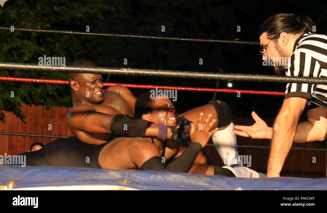 U.S. Army Reserve Sgt. Trenty Watford, a microwave communications specialist with the 4th Sustainment Command (Expeditionary), as ‘T-Ray,’ performs a choke hold on ‘K.O. Cox’ in a professional wrestling match in San Antonio, Texas, on Jun. 3, 2017, as referee ‘Jimmy K’ watches closely.  The U.S Army Reserve is full of citizen-soldiers who balance a civilian job with their service in the military.  This balance can be a challenge, but these warrior-citizens persevere, keeping the U.S. Army Reserve a capable, combat-ready and lethal force. Stock Photo