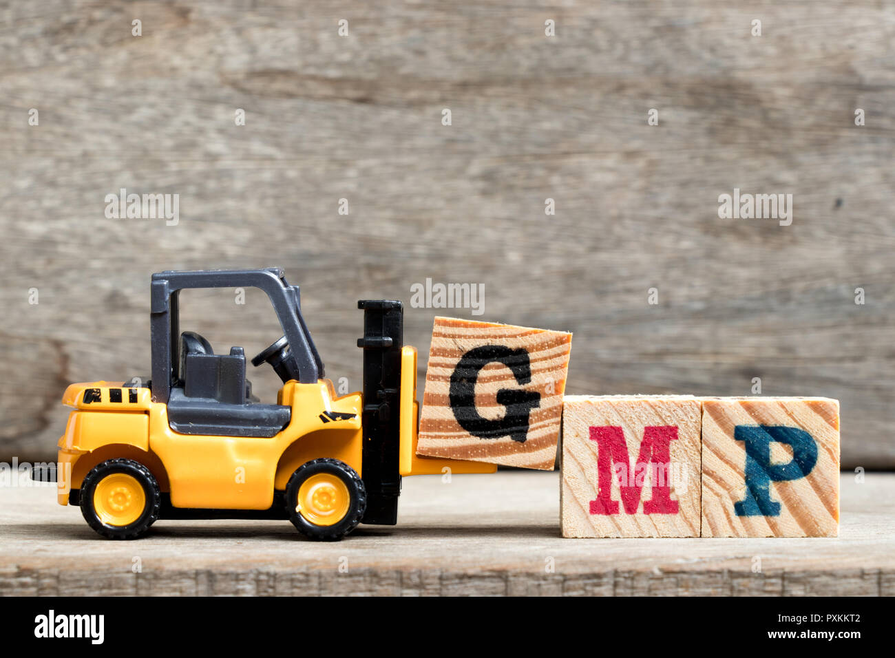 Yellow plastic forklift hold letter G to complete word GMP (Abbreviation of Good Manufacturinc Practice) on wood background Stock Photo