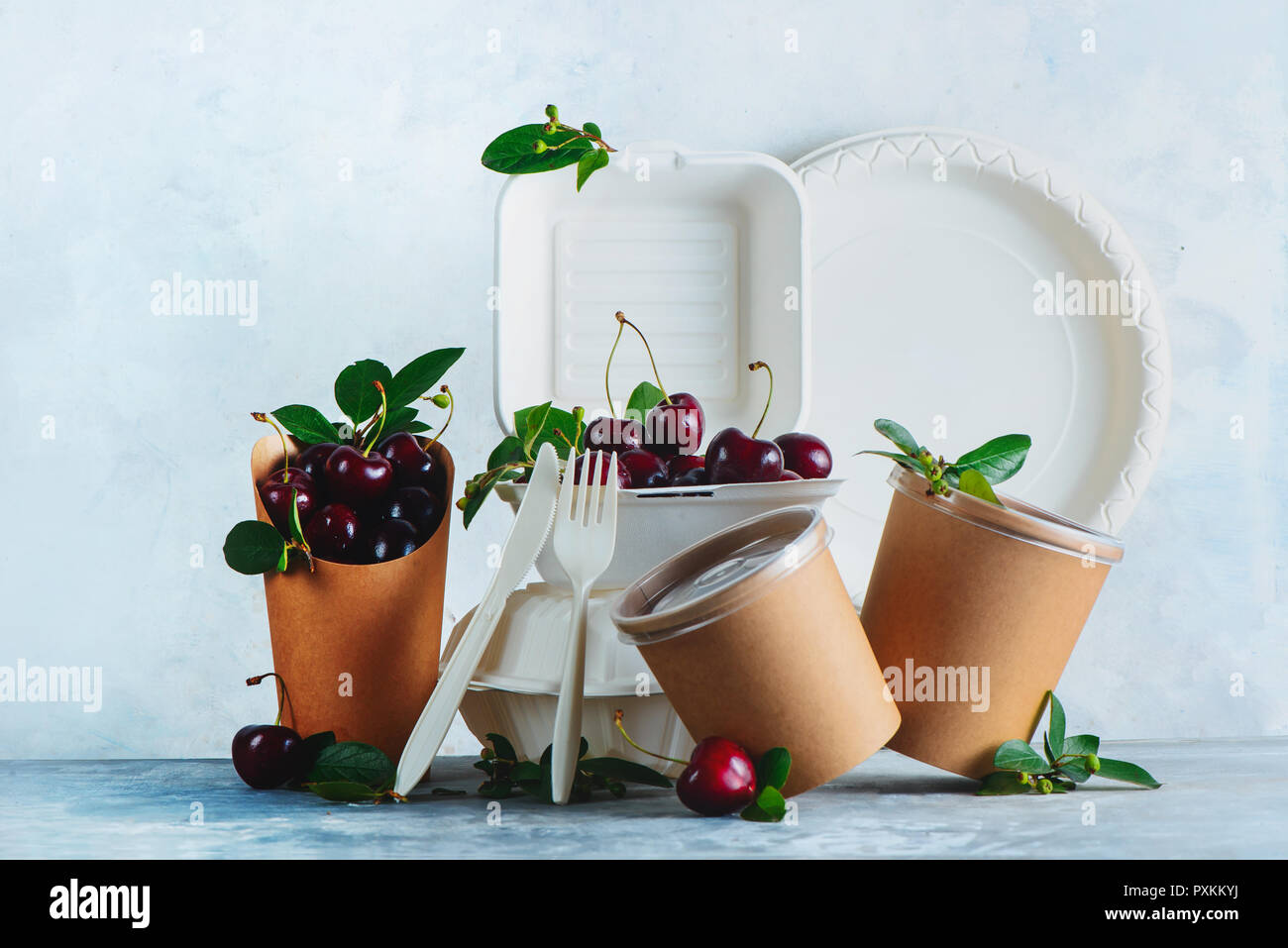 Catering disposables, cups, plates and containers with cherries. Eco