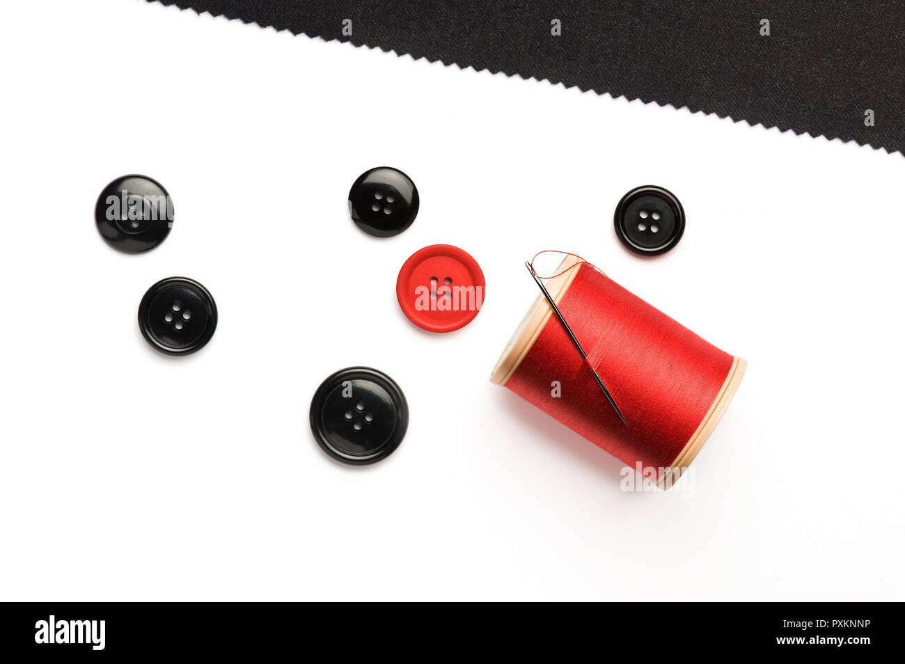 Black and red buttons, a reel of red cotton and black cloth Stock Photo