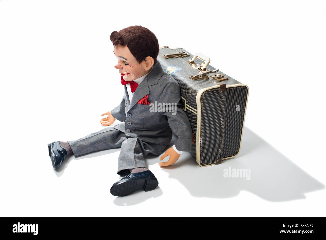 A ventriloquist dummy sitting against a suitcase Stock Photo