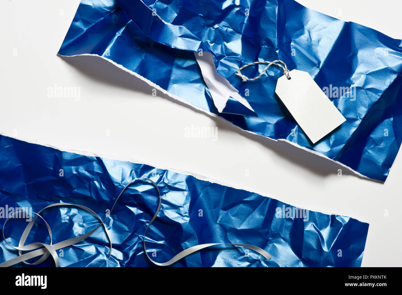 Used blue wrapping paper, silver ribbon and gift tag Stock Photo