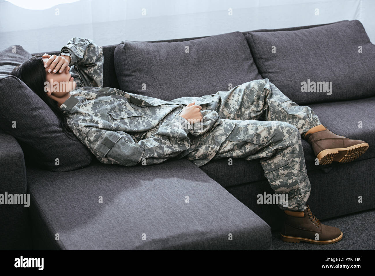Female Soldier In Military Uniform With Ptsd Lying On Couch Stock