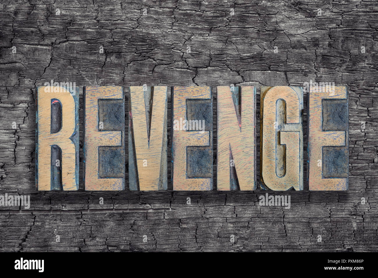 revenge word made from vintage letterpress type on burned wood background Stock Photo
