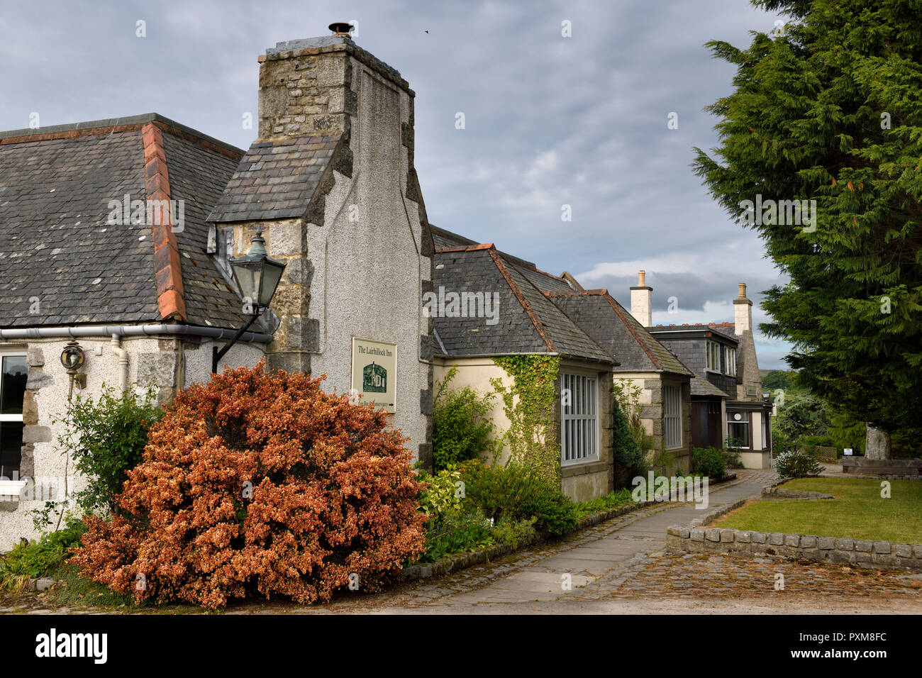 The Lairhillock Inn classic Scottish Inn near Aberdeen Scotland UK with red Lena Scotch broom bush in June Stock Photo