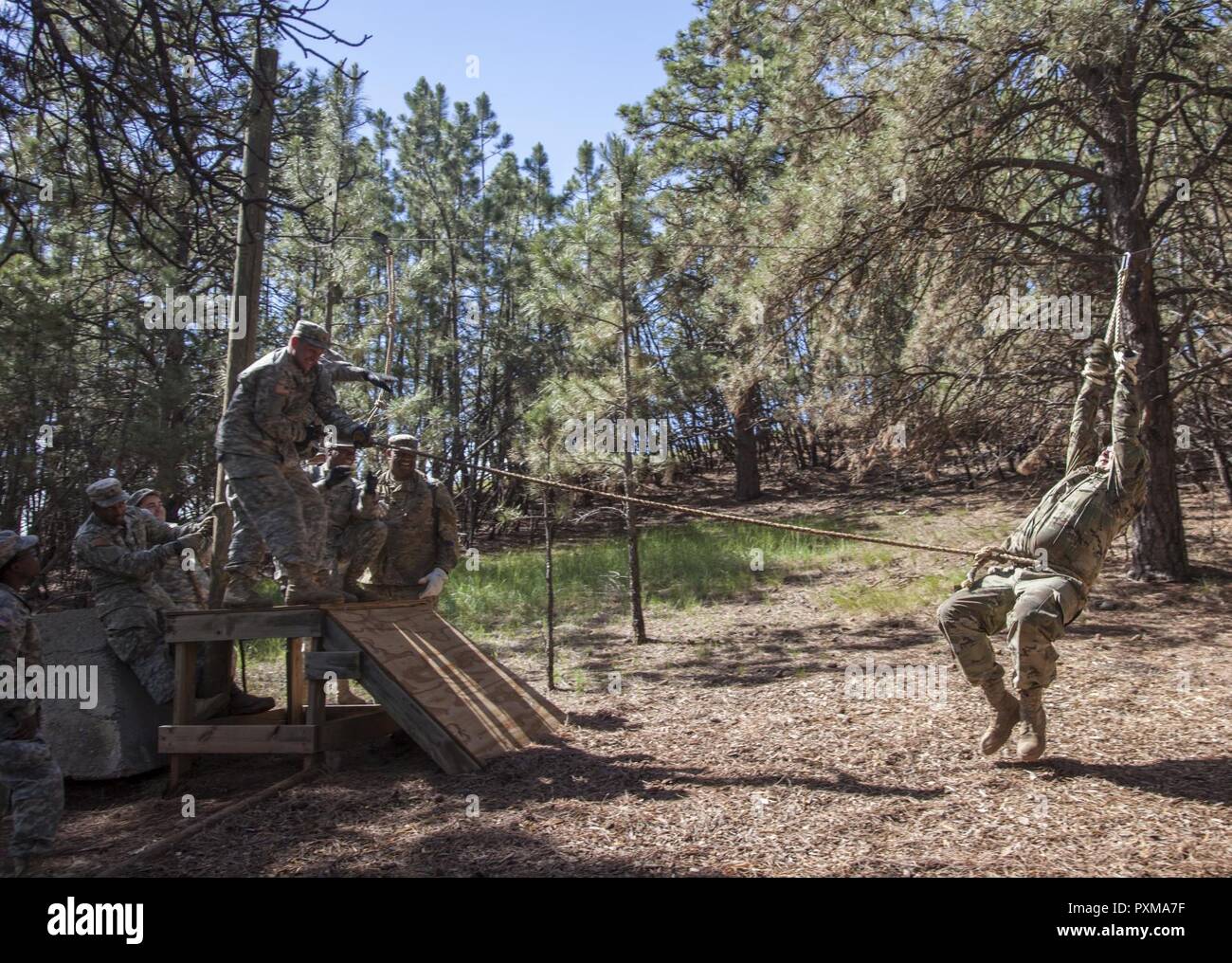 U.S. Soldiers with the 1138th Transportation Company, Missouri Army National Guard, pulls Spc. Brandon Hamilton across a rope bridge obstacle during the Leadership Reaction Course in support of the Golden Coyote exercise at West Camp Rapid, S.D., June 13, 2017. The Golden Coyote exercise is a three-phase, scenario-driven exercise conducted in the Black Hills of South Dakota and Wyoming, which enables commanders to focus on mission essential task requirements, warrior tasks and battle drills. Stock Photo