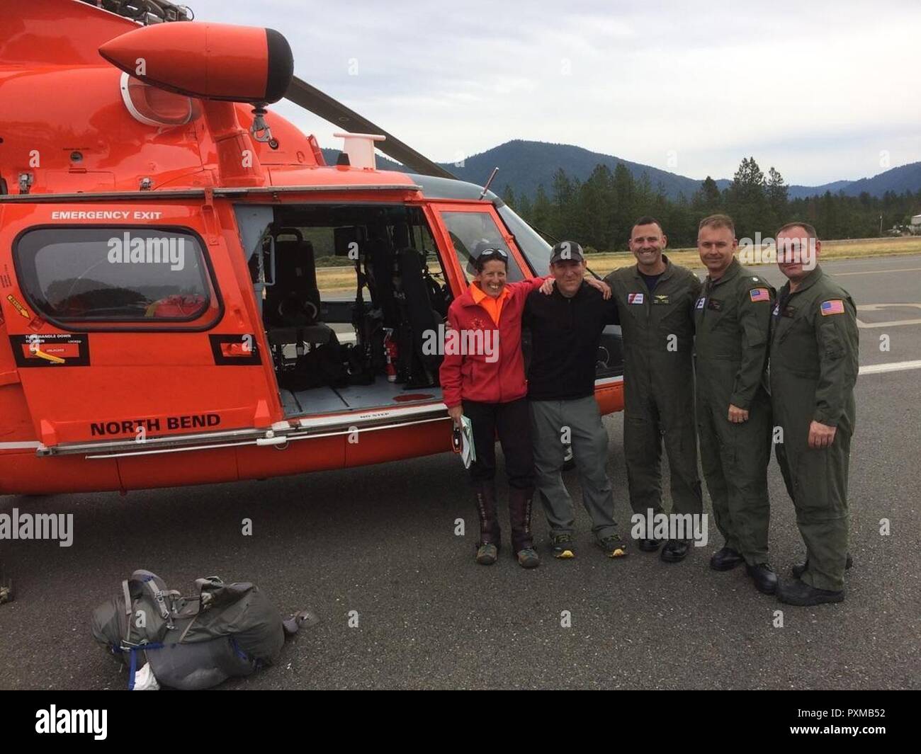 Anne McGloon, from the Josephine County Sheriff's Office and a rescued hiker stand with the aircrew of an MH-65 Dolphin helicopter from Sector North Bend at an airport in Grants Pass, Ore., June 14, 2017.    The hiker had been missing for 5 days in the Rogue River-Siskiyou National Forest after a planned 45-mile hike. Stock Photo