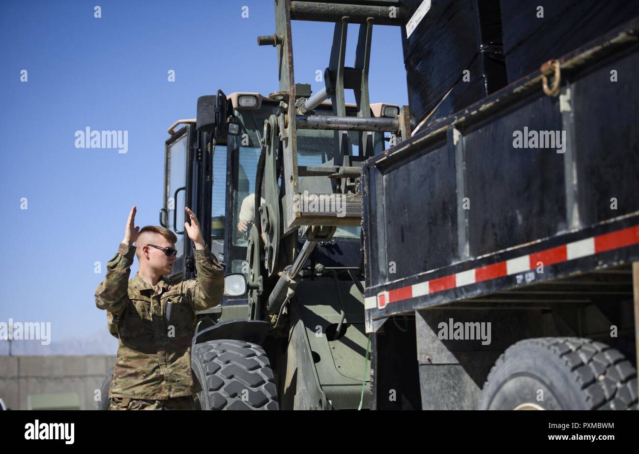 Airman 1st Class Blaine Runge directs a forklift operator, Senior Airman Giovany Tellez, both with the 455th Expeditionary Logistics Readiness Squadron traffic management office, at Bagram Airfield, Afghanistan, June 13, 2017. The 455th ELRS TMO receives vast amounts of cargo each day, and utilizes various vehicles such as forklifts and flatbed trucks to get them where they need to be. Stock Photo