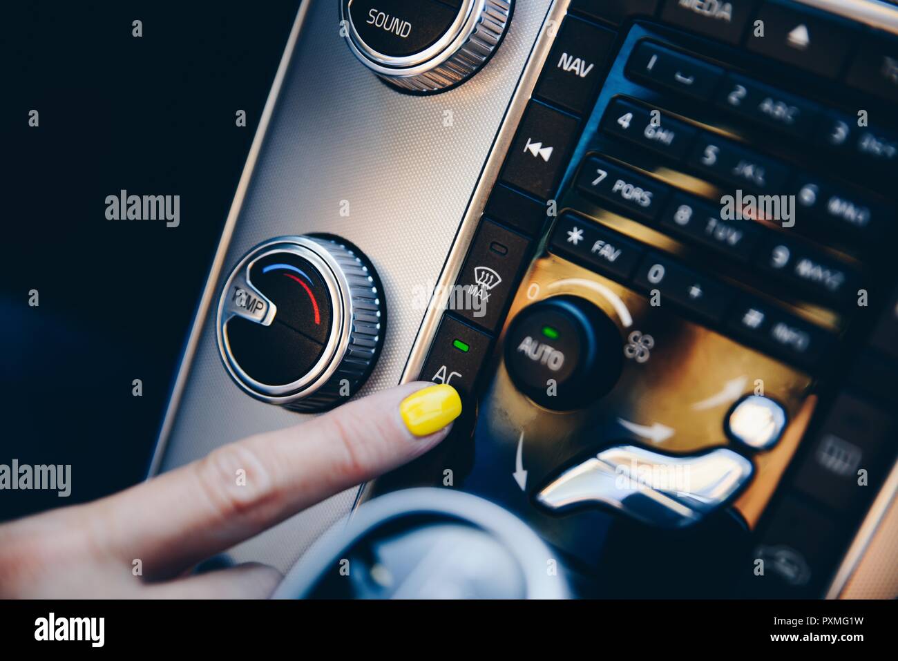 Woman turning on air conditioner on car automatic air conditioner panel