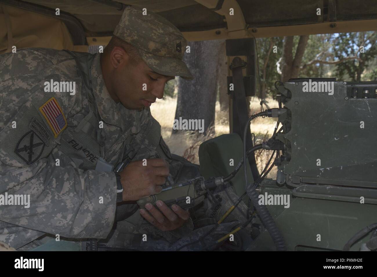 U.S. Army Sgt. 1st Class Armando Filmore, an Observer Controller Trainer (OCT) from the 3rd of the 290th Regiment, installs a Single Channel Ground and Airborne Radio System (SINCGARS) during the 91st Training Division’s Warrior Exercise on Fort Hunter Liggett, Calif. June 15, 2017. SINCGARS uses 25 kHz channels in the very high frequency FM band, from 30.000 to 87.975 megahertz. Stock Photo