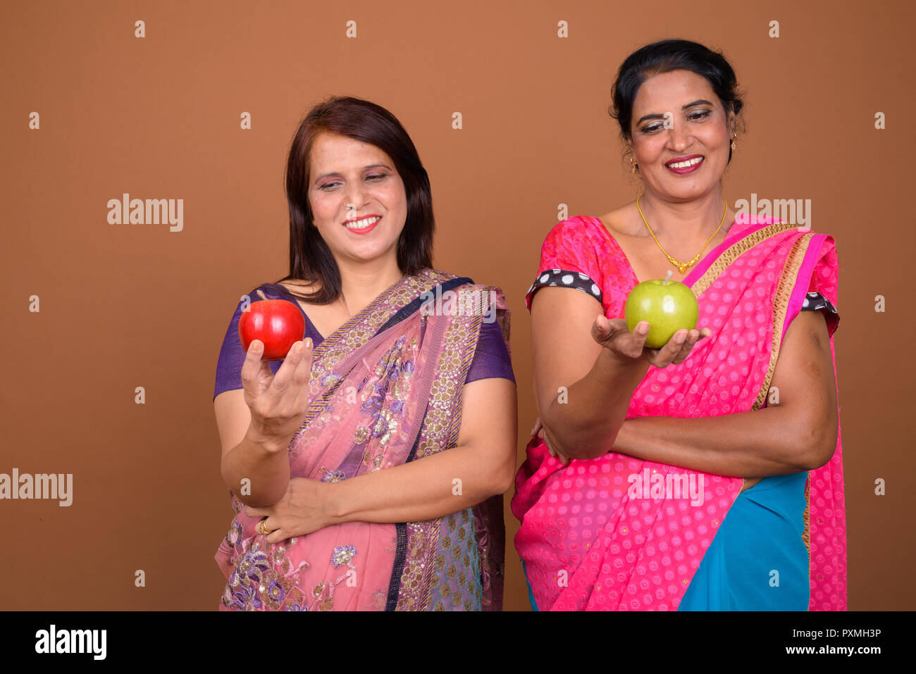 Two happy Indian woman holding healthy apple fruit Stock Photo