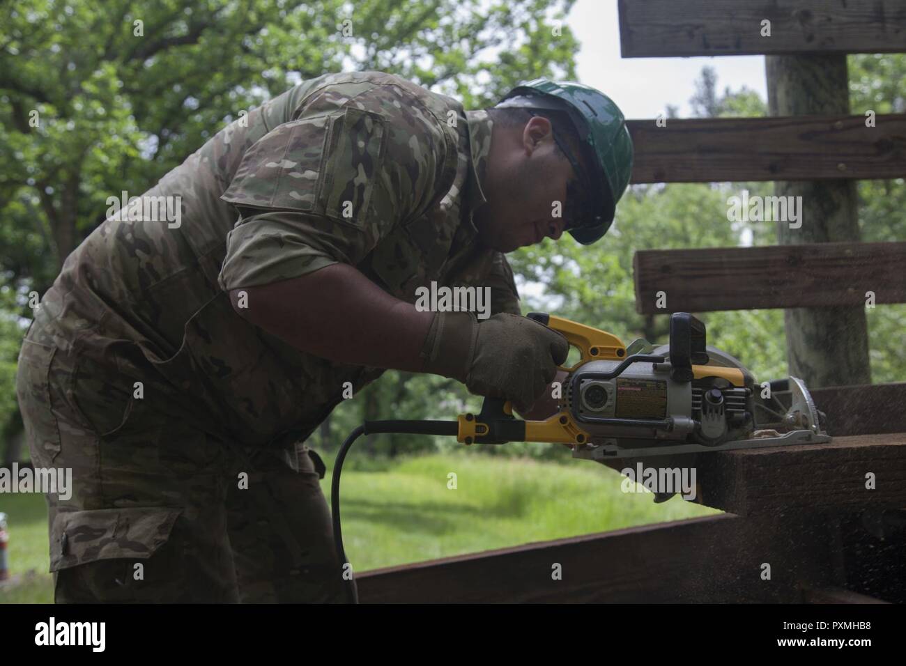 Lance Cpl. Al Frederiksen, 3rd Construction Battalion, Danish Army, makes a cut with a rotary saw for construction of a foot bridge at Custer State Park in support of the Golden Coyote Exercise, Custer, S.D. June 16th, 2017. The Golden Coyote exercise is a three-phase, scenario-driven exercise conducted in the Black Hills of South Dakota and Wyoming, which enables commanders to focus on mission essential task requirements, warrior tasks and drills. Stock Photo