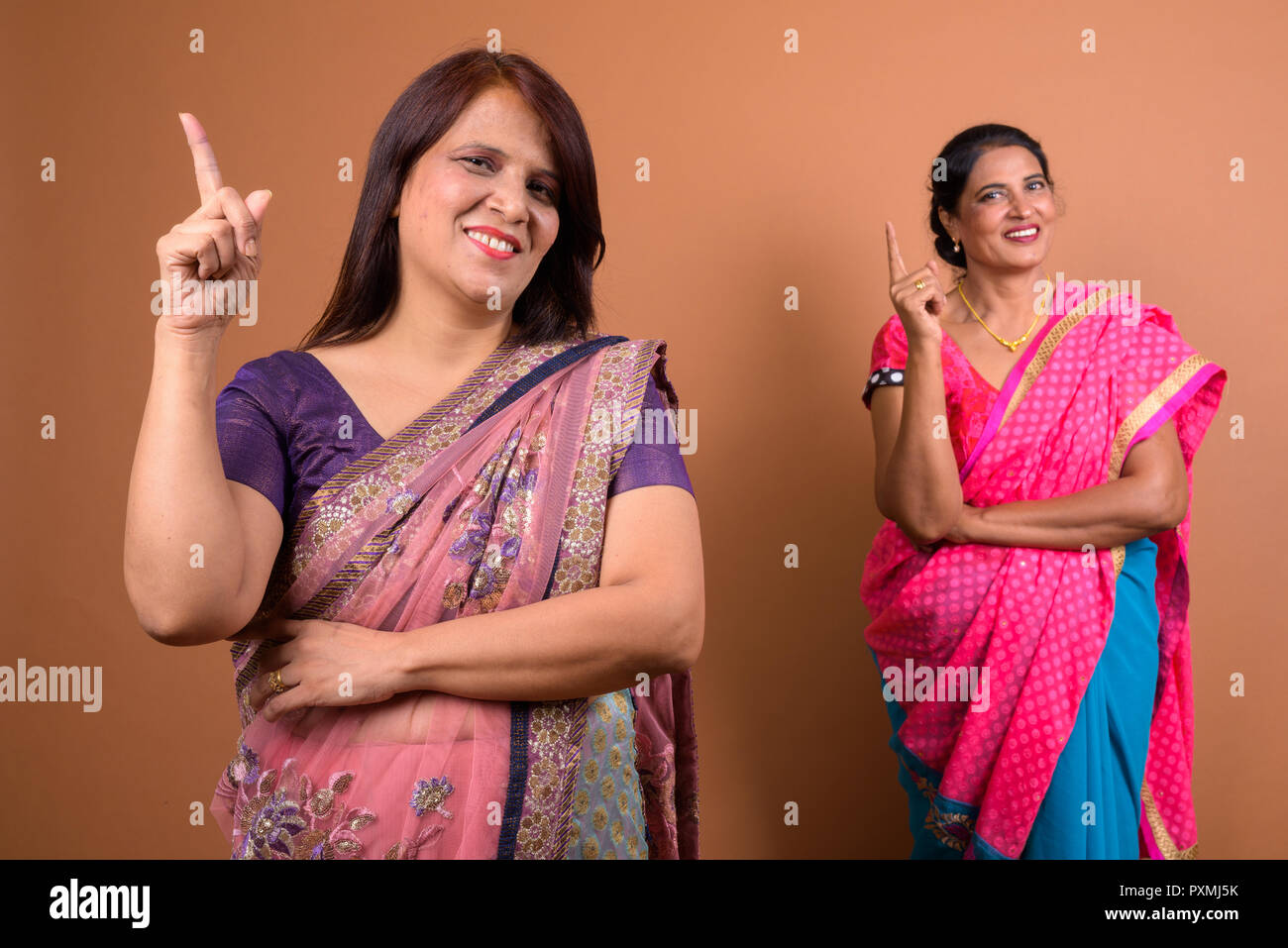 Portrait of two happy Indian woman pointing finger up Stock Photo