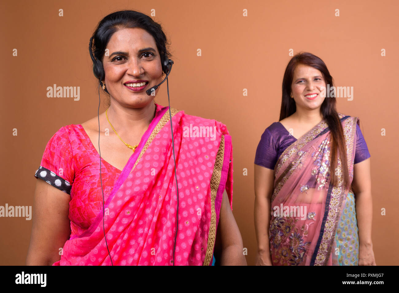 Happy mature Indian woman call center representative wearing headset Stock Photo