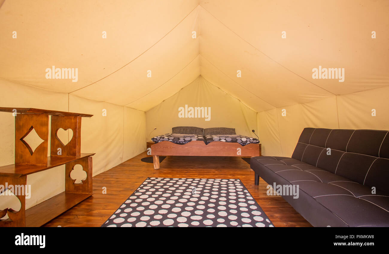Glamping tent interior with real bed, sofa and shelves in Adrenaline Check eco camp in Slovenia. Stock Photo