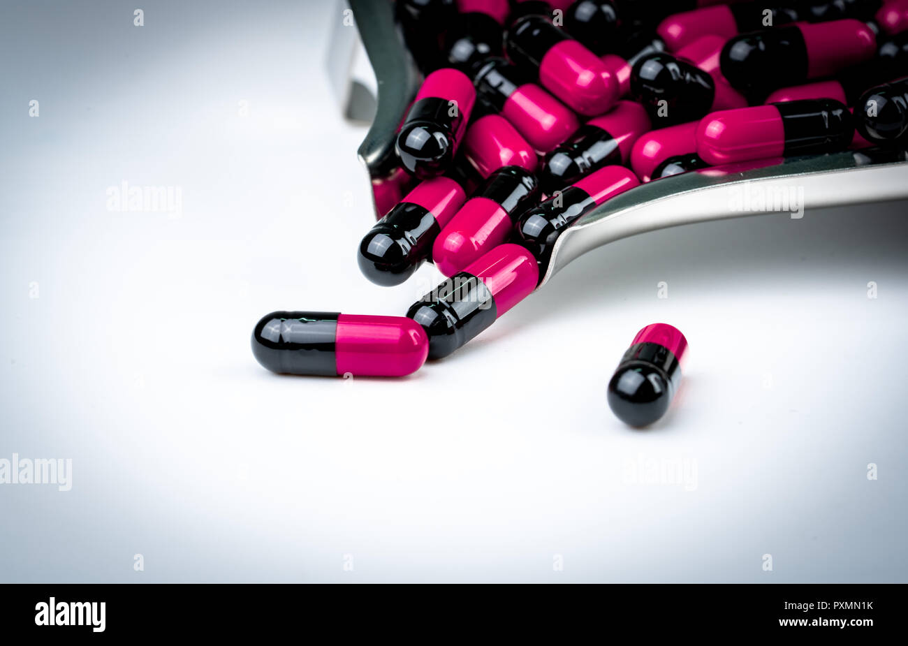 Pinkblack capsule pills on drug tray. Antibiotics drug resistance